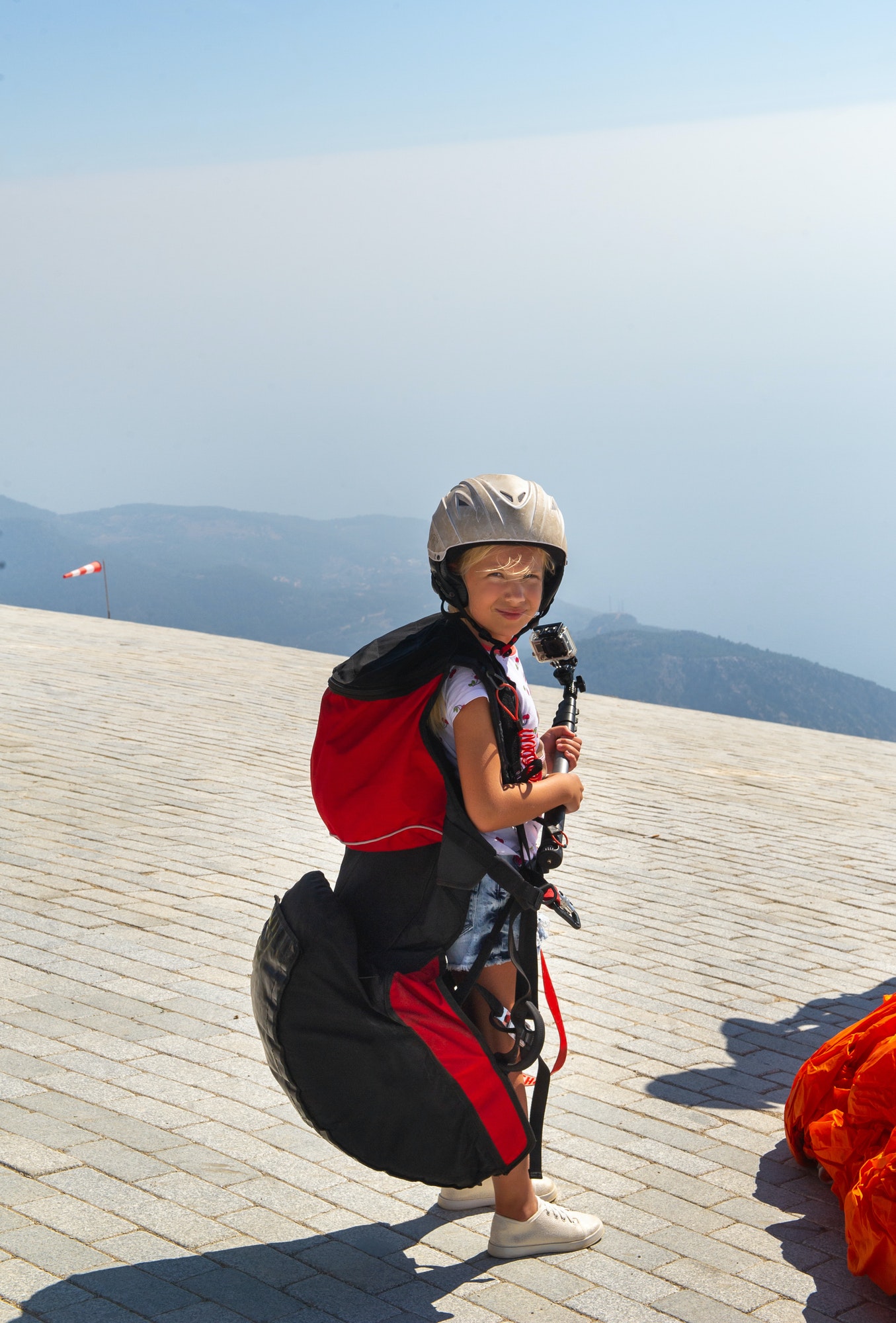 a-little-girl-in-paragliding-gear-and-with-a-camera-stands-on-the-edge-of-mount-babadag-turkey-1.jpg